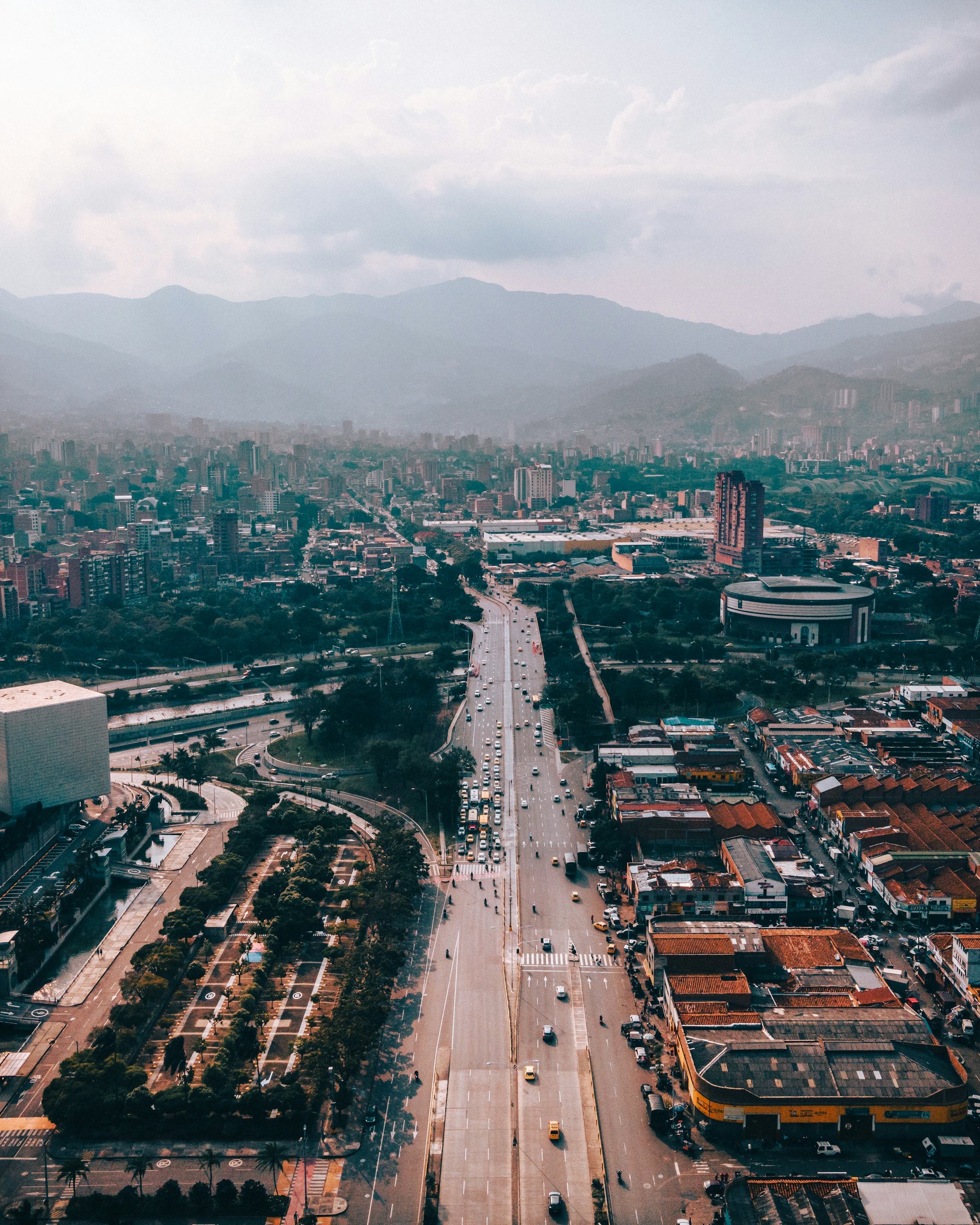 An arterial avenue threading through Medellín at first light, the Andes hazed behind the city
